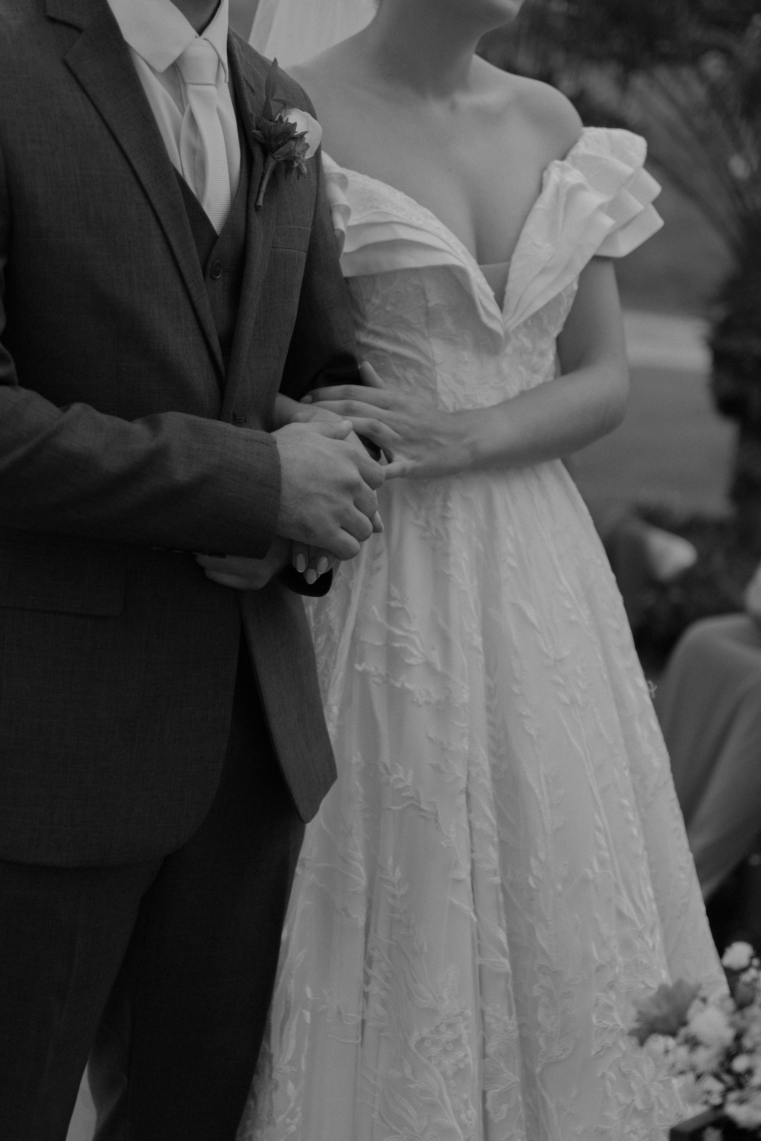 A black and white close-up of wedding attire details during the ceremony.
