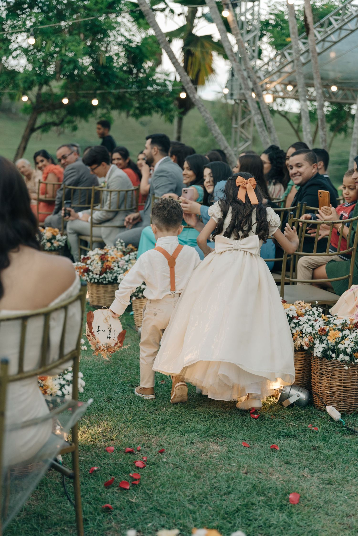 Wedding guests enjoying outdoor reception with string lights and floral decorations.