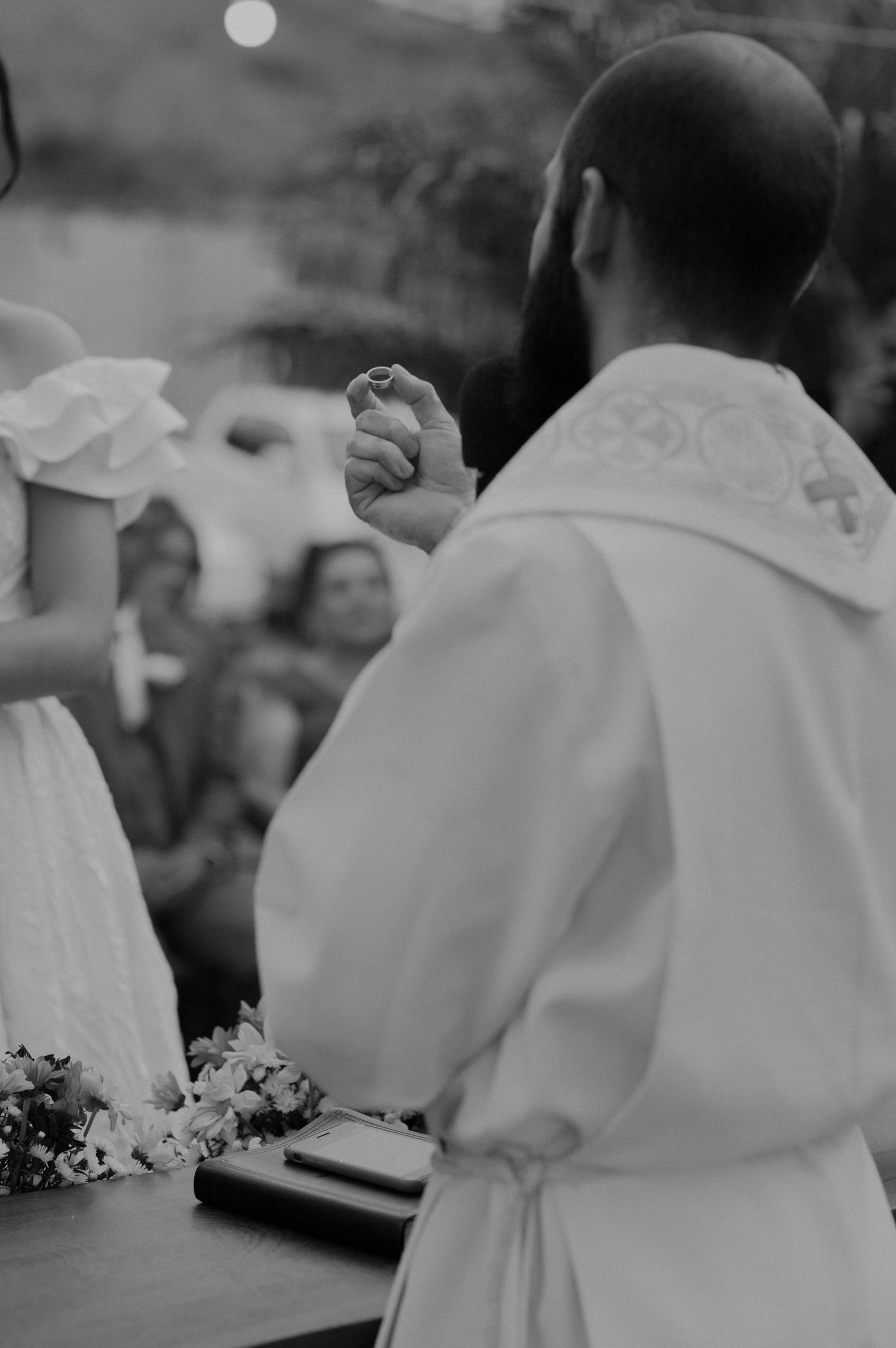 Black and white photo of priest and bride during outdoor wedding ceremony.