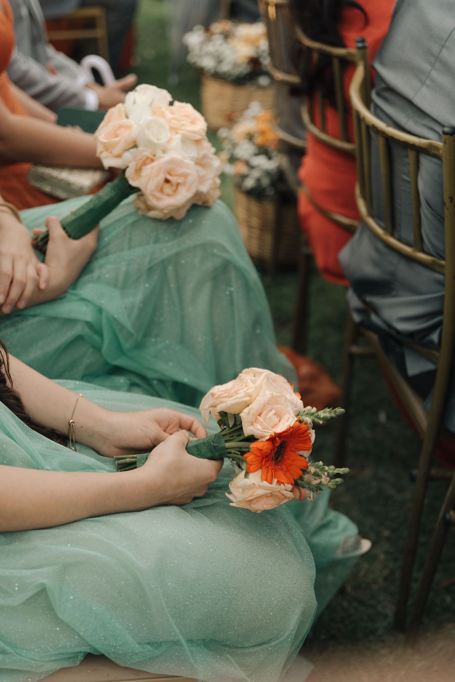 Bridesmaids in mint green dresses hold peach and coral floral bouquets.