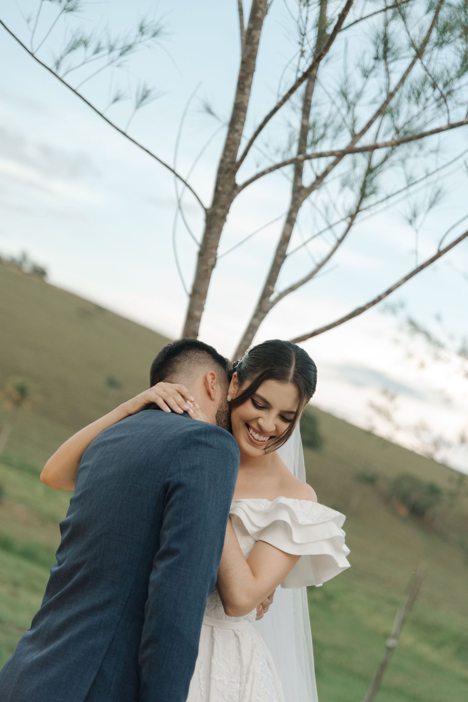 An intimate wedding moment captured outdoors with a bride in ruffled dress and groom in navy.