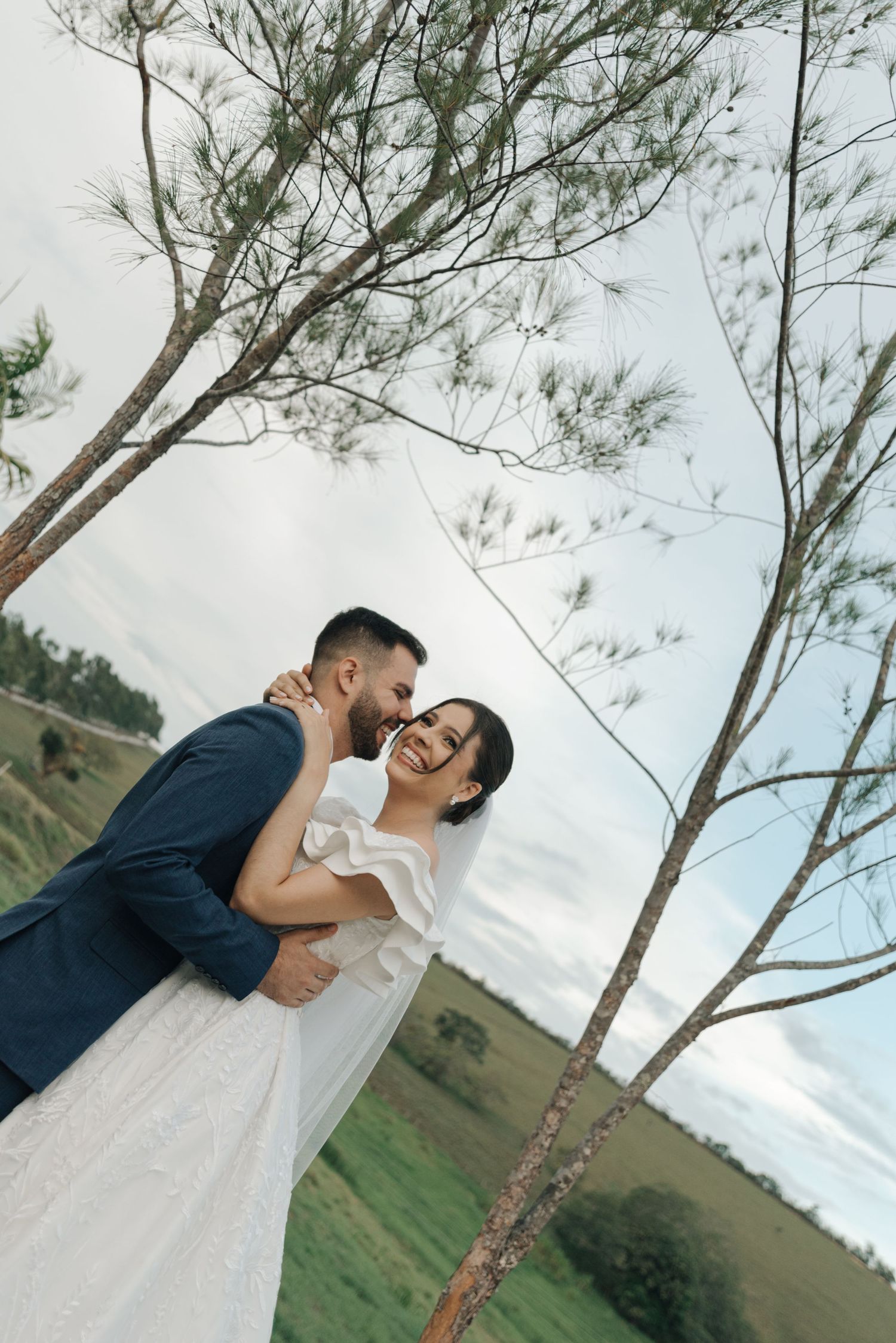 A candid wedding photo showing laughter and joy between newlyweds in a natural setting.