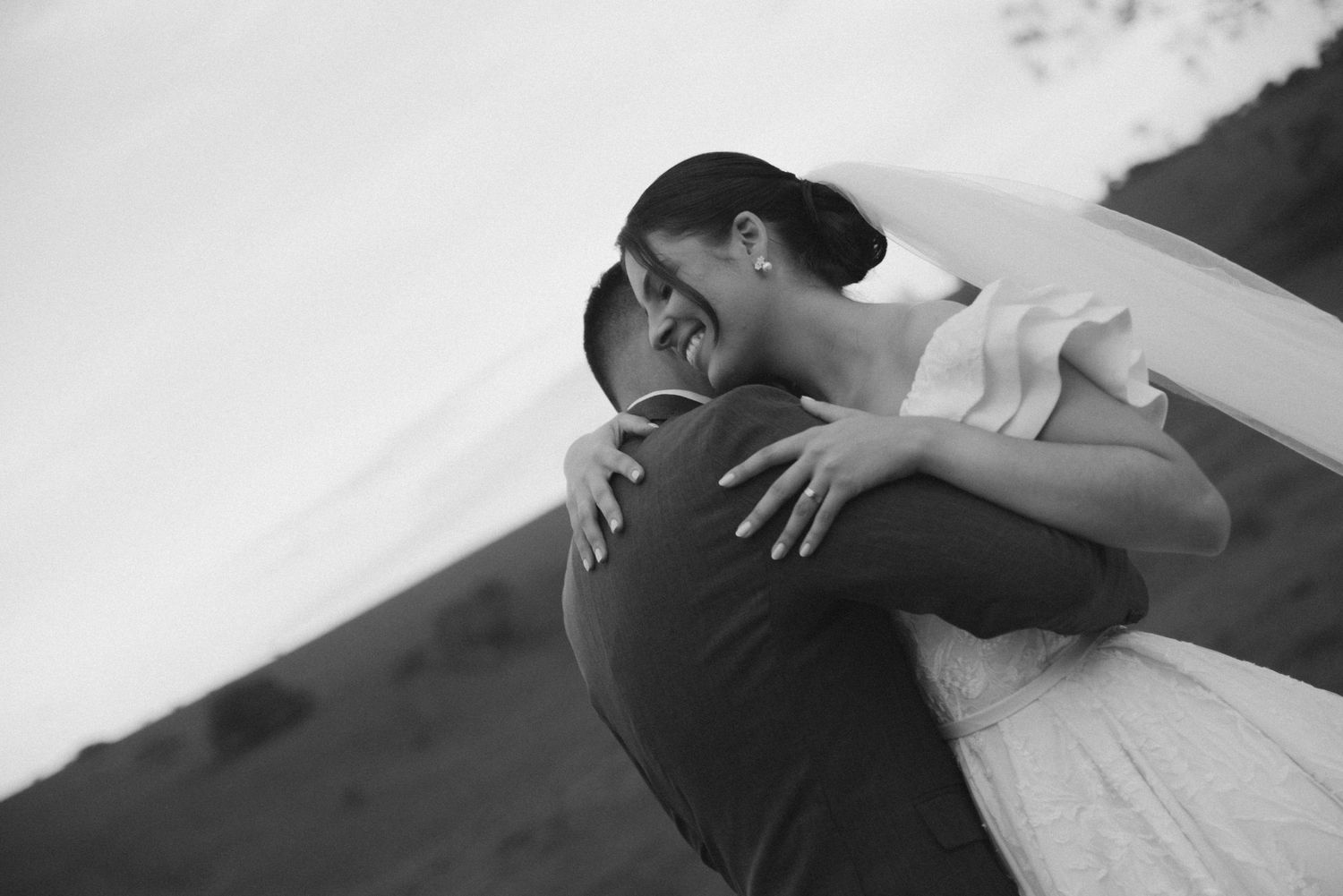 A romantic black and white wedding photo shows an intimate embrace between newlyweds in formal attire.
