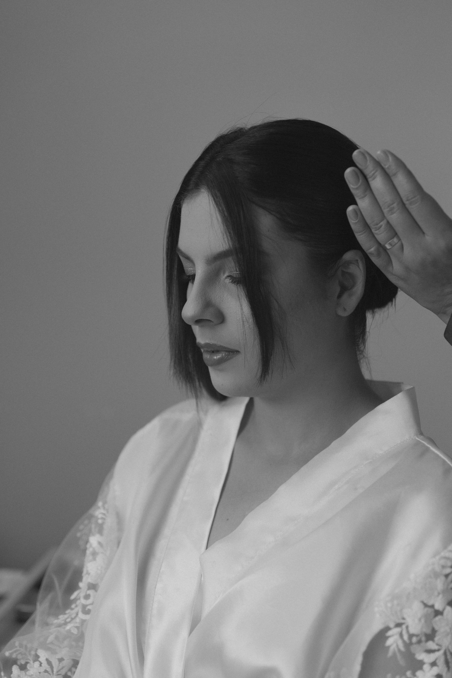 Black and white portrait of wedding preparation with lace robe and elegant styling.