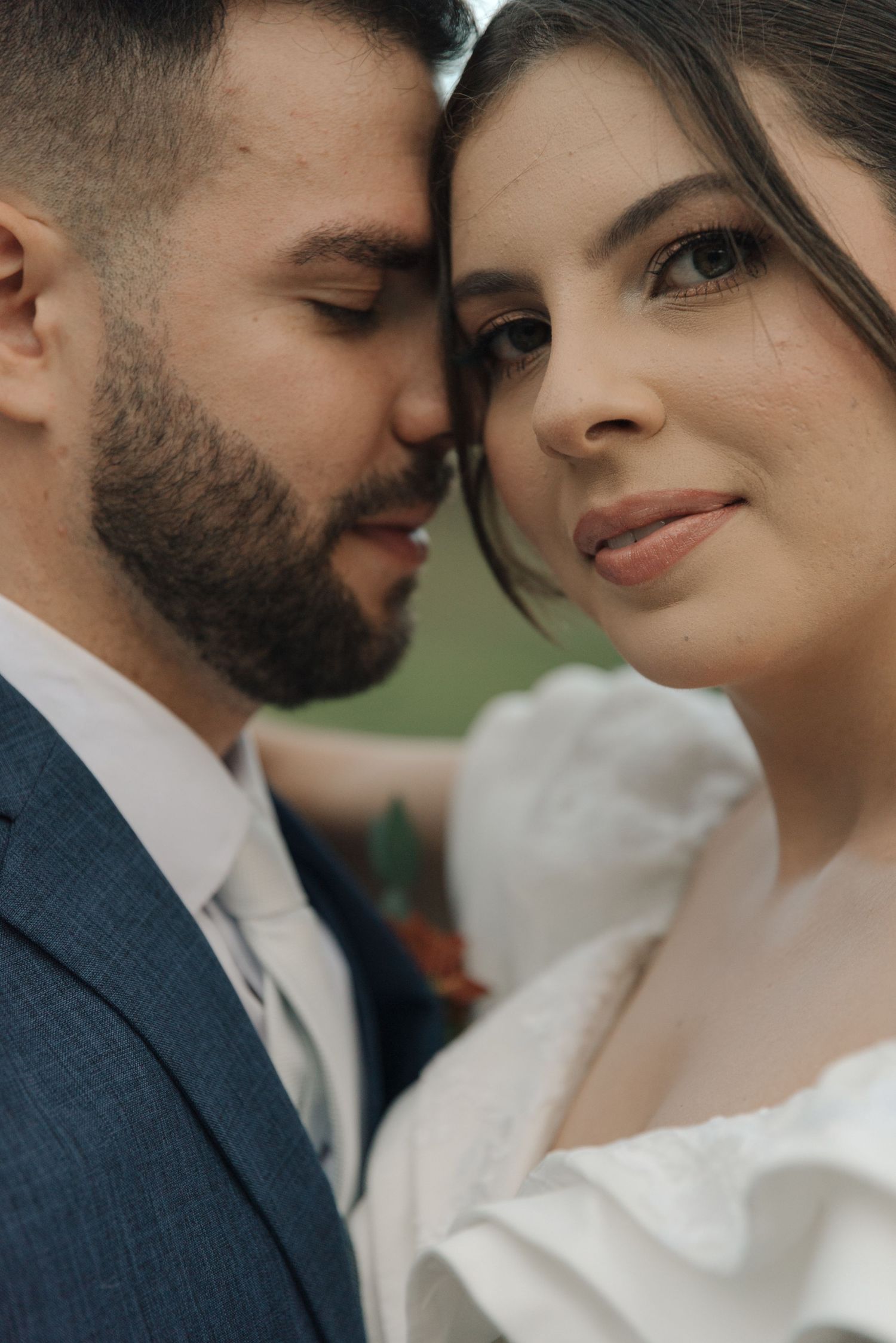 Intimate close-up portrait of newlyweds sharing a tender moment outdoors.