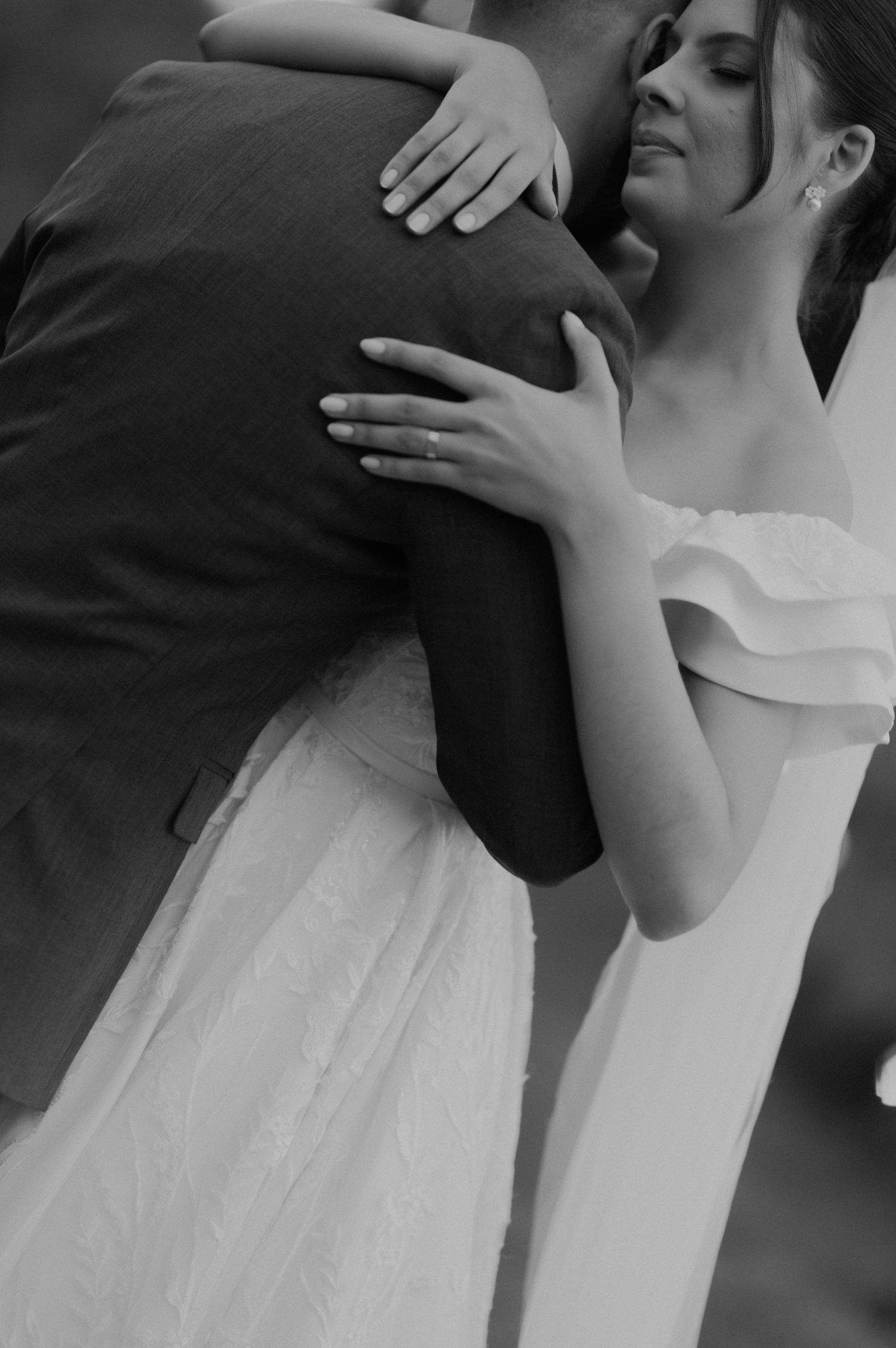 Black and white close-up of bride and groom embracing, showing emotional connection.