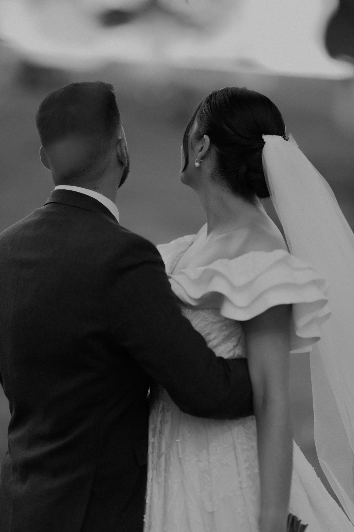 A black and white portrait of a wedding couple in an intimate embrace.