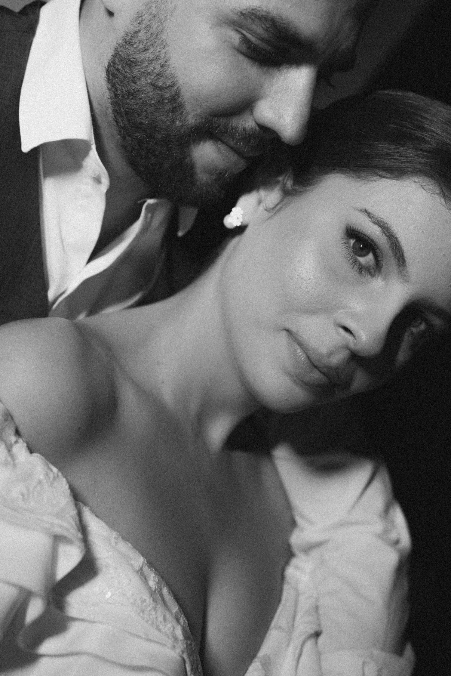 A dramatic black and white close-up portrait of newlyweds in an intimate moment.