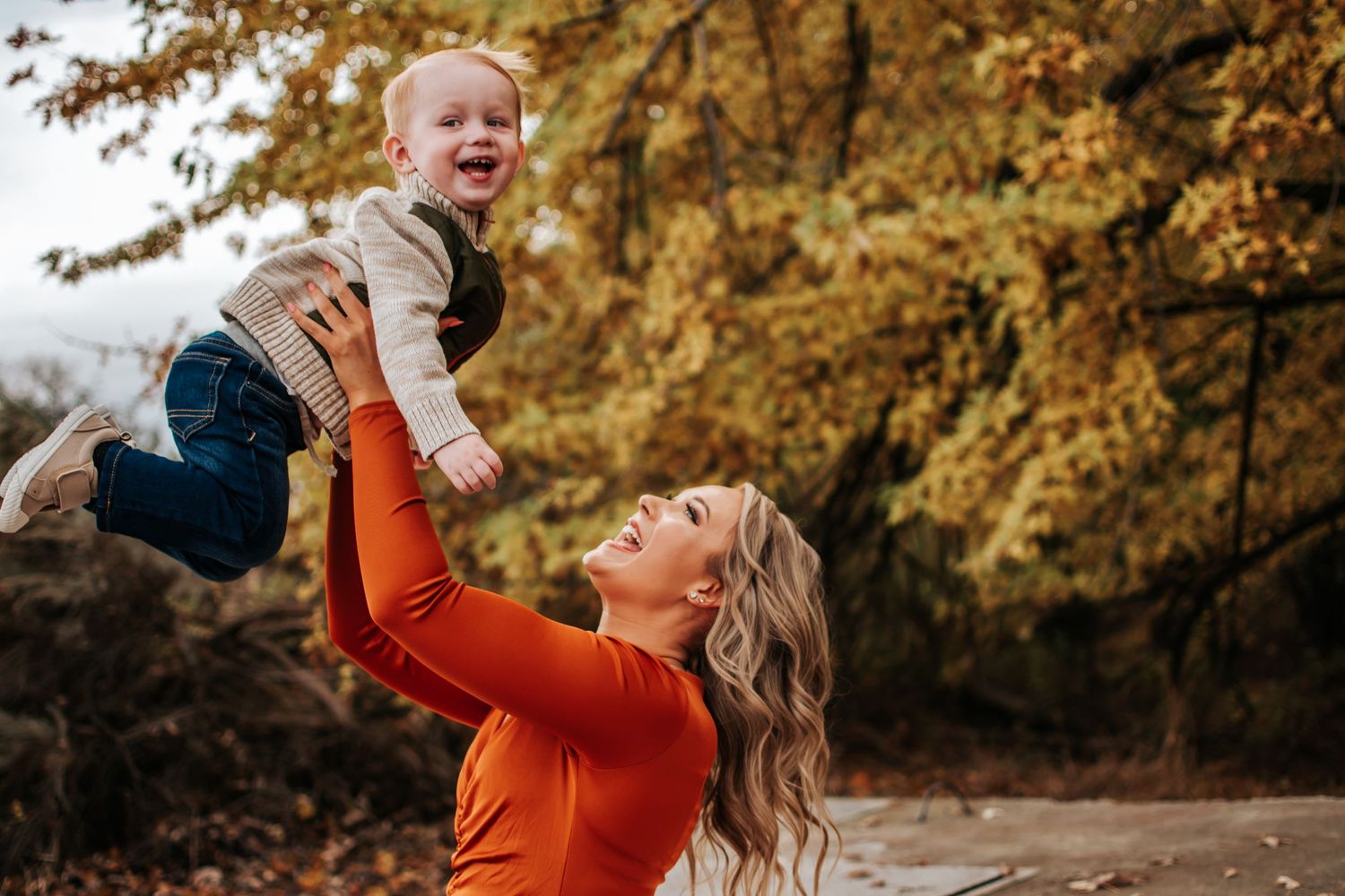 Parent playfully lifting child in air during fall outdoor photo session in Richland, Washington.