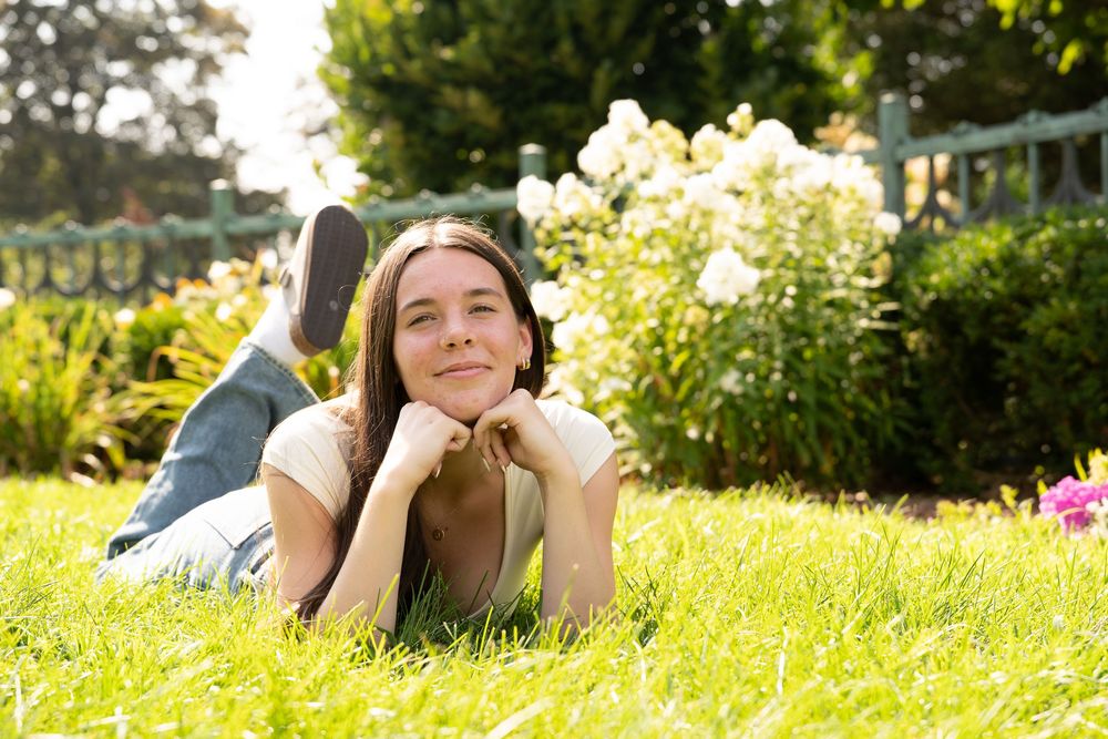 Person lying on grass in garden with flowers in background on sunny day.