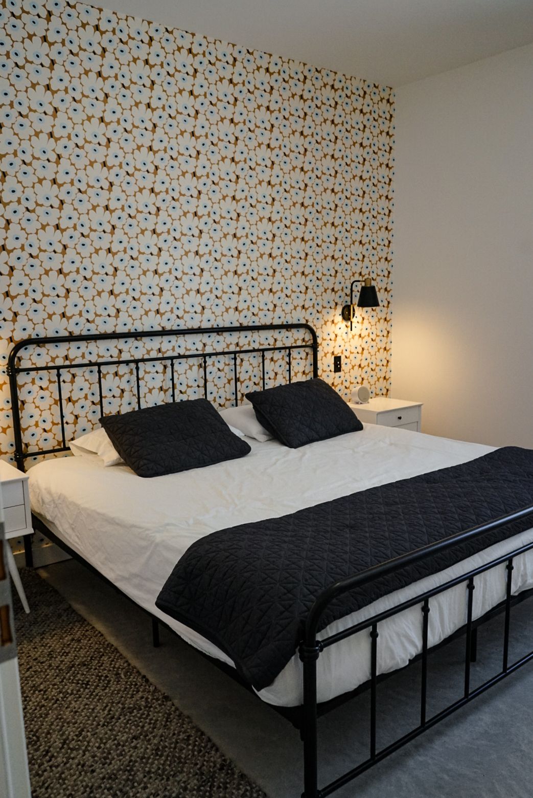 Bedroom with black metal bed frame and floral wallpaper featuring a black and white color scheme.