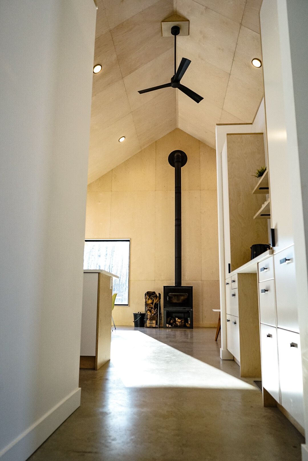 Long hallway with vaulted ceiling, white walls, and concrete flooring.