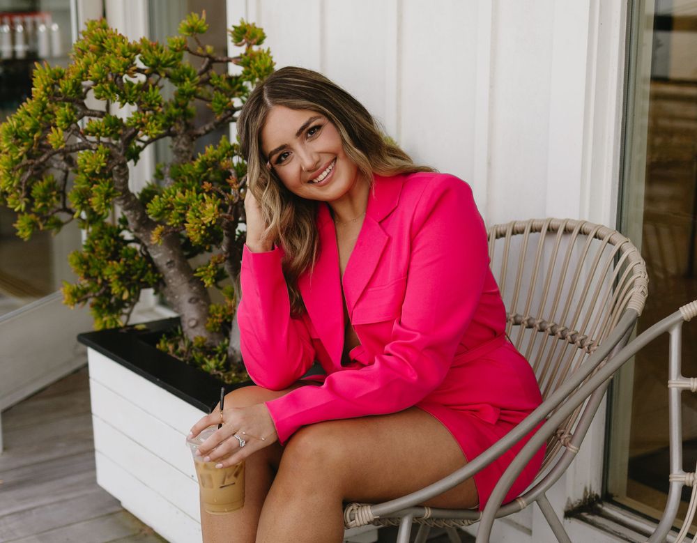 A bright pink blazer outfit styled with fun patterned socks for a casual yet chic look on a porch setting.