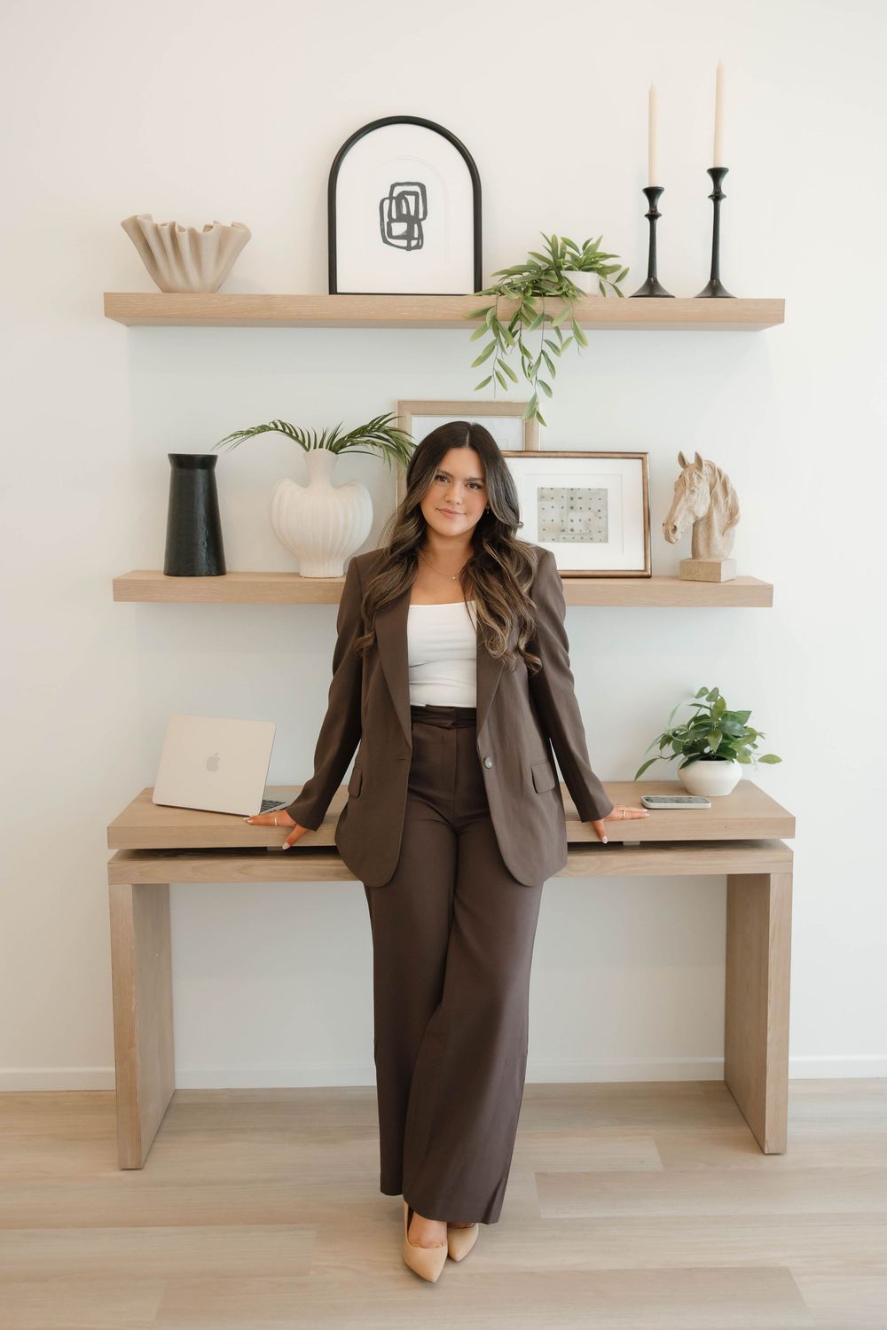 Professional brown business suit styled with modern accessories and displayed on wooden shelves with minimalist decor.