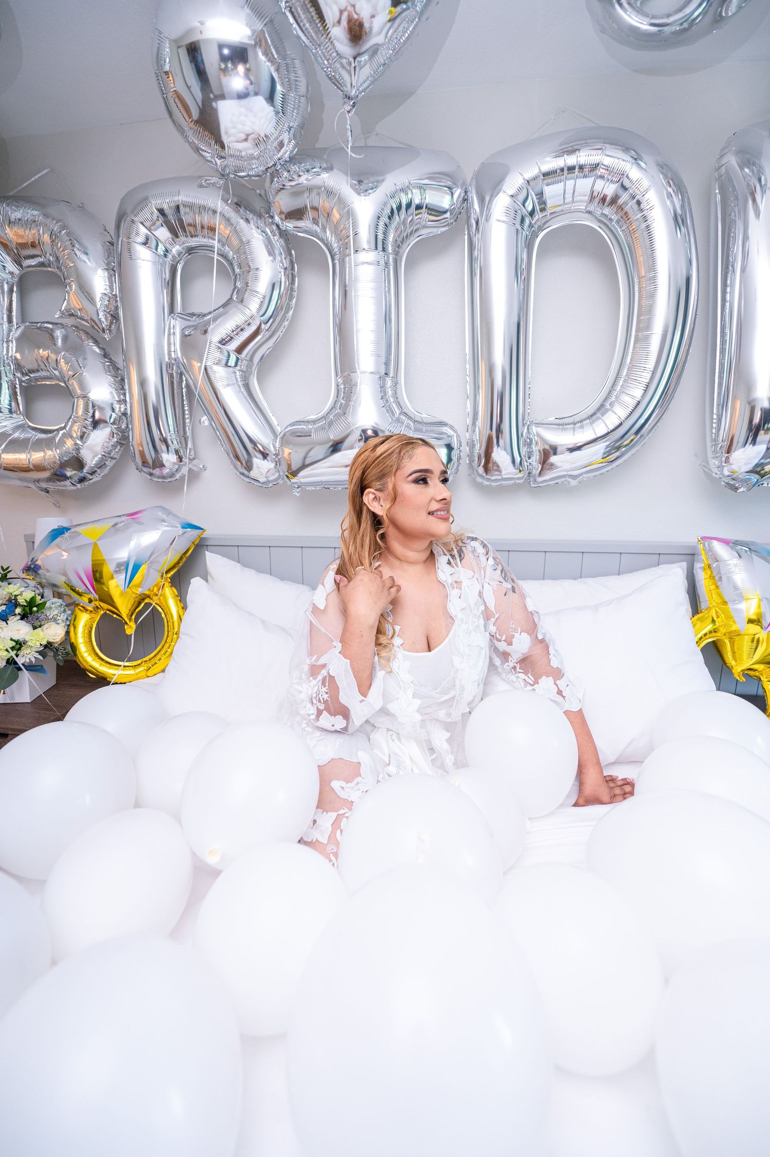 Bridal portrait with silver BRIDE balloons and white decorations.