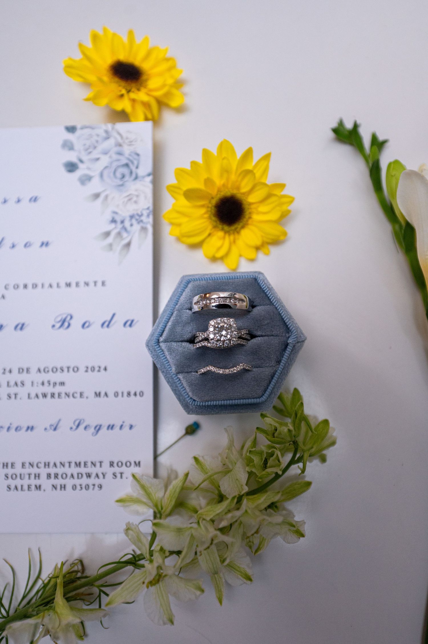 Wedding invitation with sunflowers and engagement rings in gray velvet box.