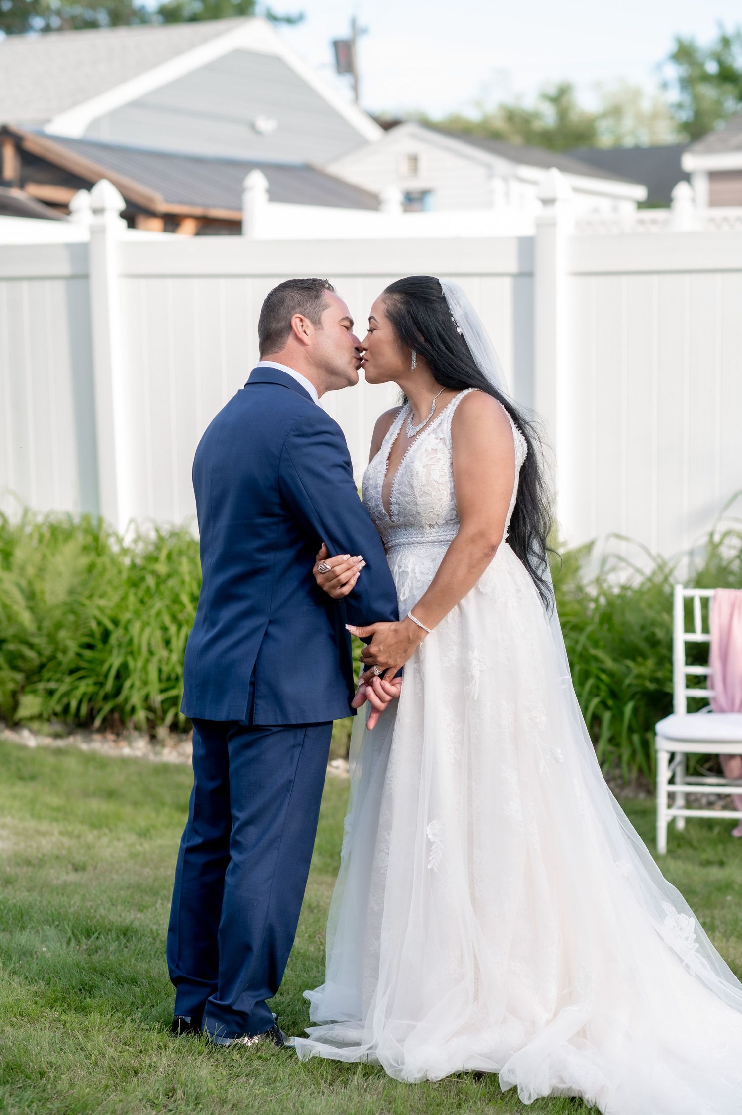 A tender wedding kiss shared between newlyweds in an outdoor garden setting.