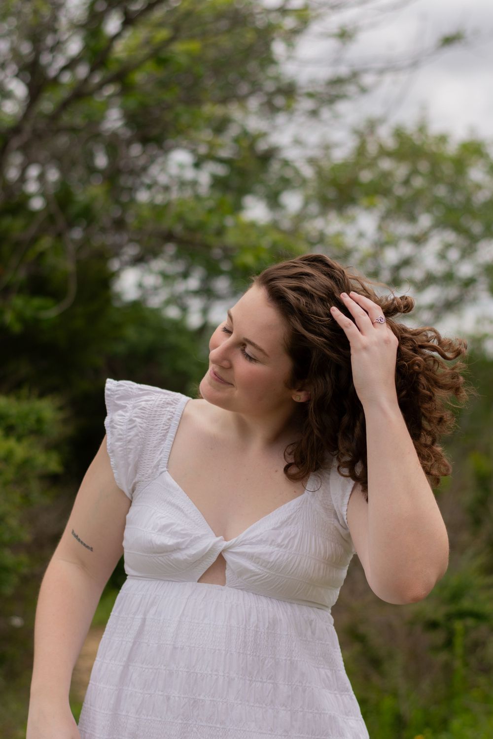 A Fort Worth spring grad tosses her curly hair to one side during a candid, in-between moment at her graduation portrait session.