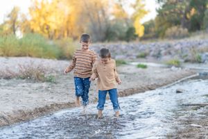 Two people walking barefoot through shallow stream water.