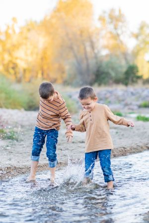 People splashing and playing in shallow stream water during autumn.