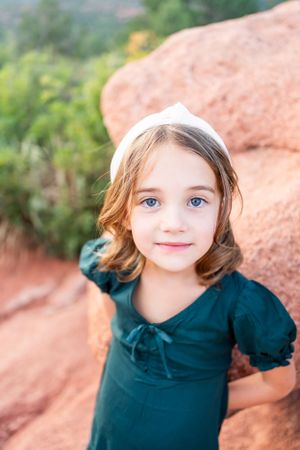 Portrait against red rocks with emerald dress and white headband.