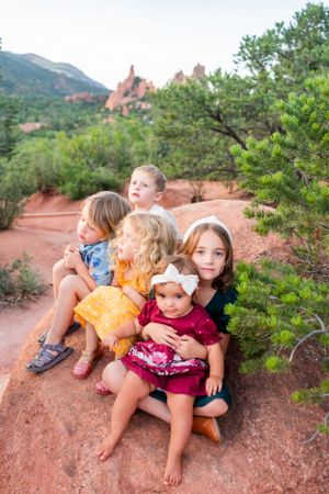 Group photo on red rocks with mountain landscape and pine trees in background.