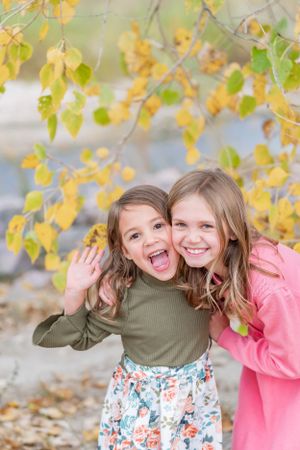 Two people sharing joyful moment under yellow autumn leaves.