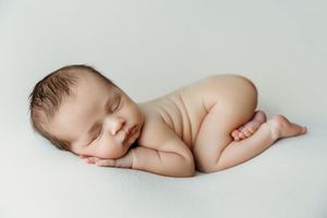 Minimalist newborn photography series on white background showing peaceful sleeping pose.