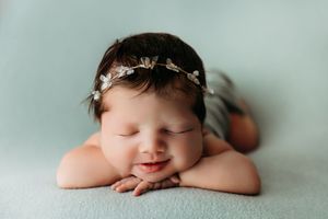 Delicate newborn photography series on soft mint background with floral headpiece.