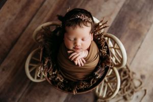 Artistic newborn portraits in vintage metal basket with rustic wooden background.
