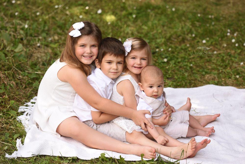 A collage of family portraits showing children in white clothing sitting together on grass during an outdoor photo session.