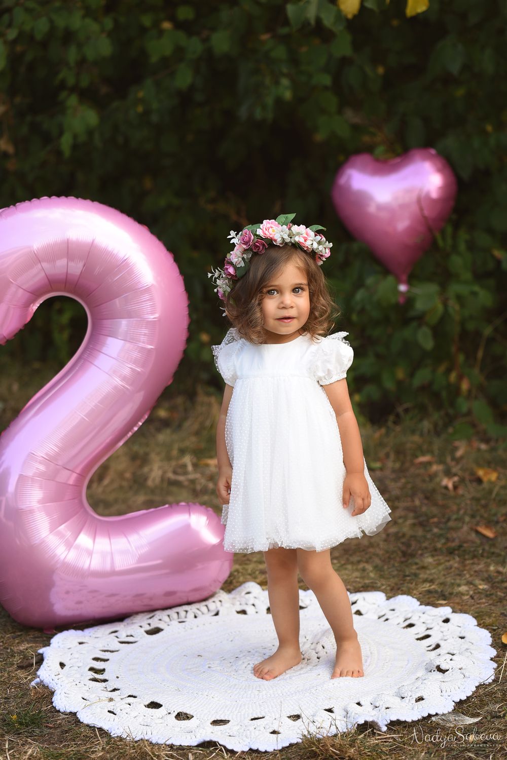 A series of photos showing a white lace dress and pink heart-shaped balloons against a natural outdoor backdrop.