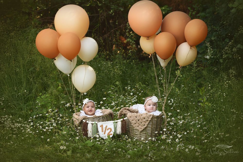 Peachy orange and white balloons arranged outdoors against natural green foliage background.