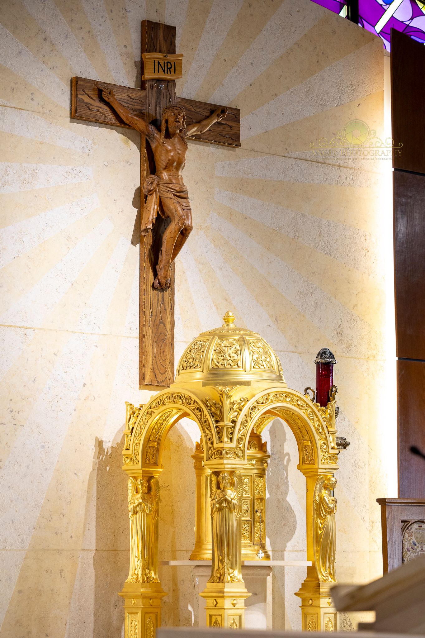 Wooden crucifix and ornate golden altar display in church sanctuary.