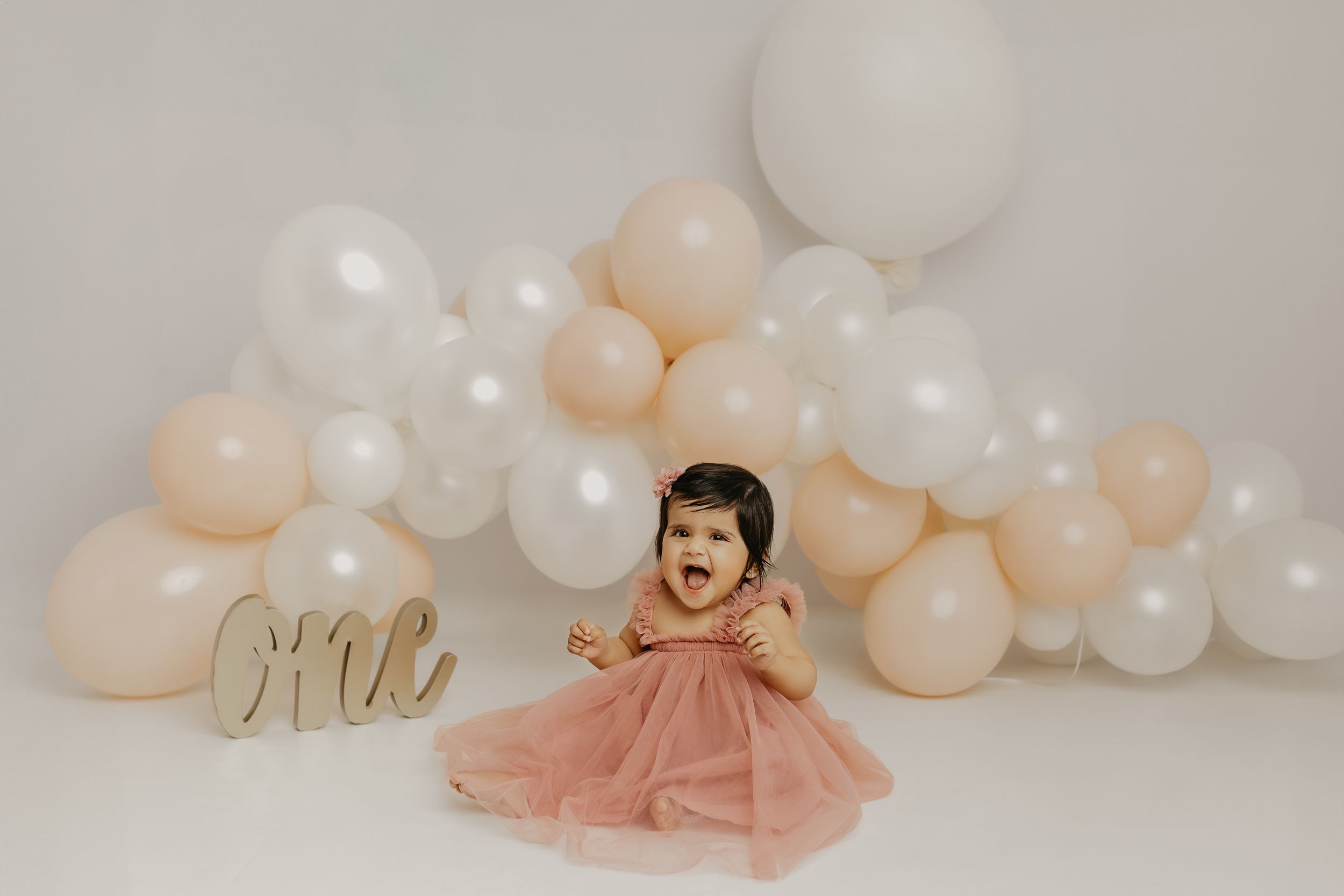 Maternity celebration setup with balloon garland and gold 'Mrs' sign.