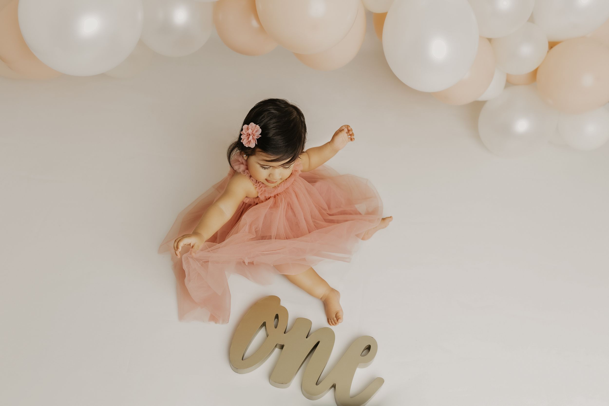 Playful maternity poses with balloon garland and metallic signage.
