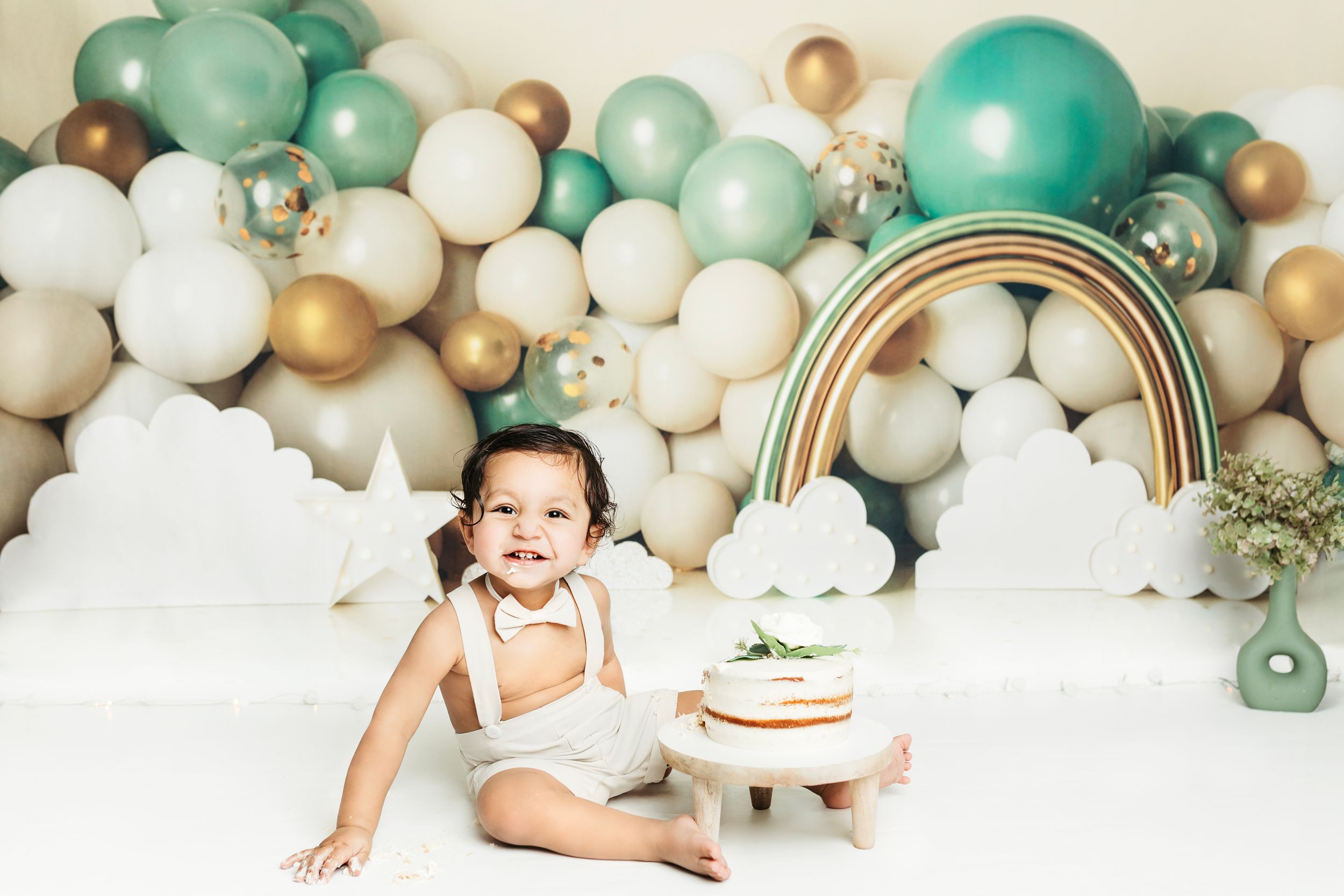 Elegant balloon arch in mint green, gold and white with cake display.