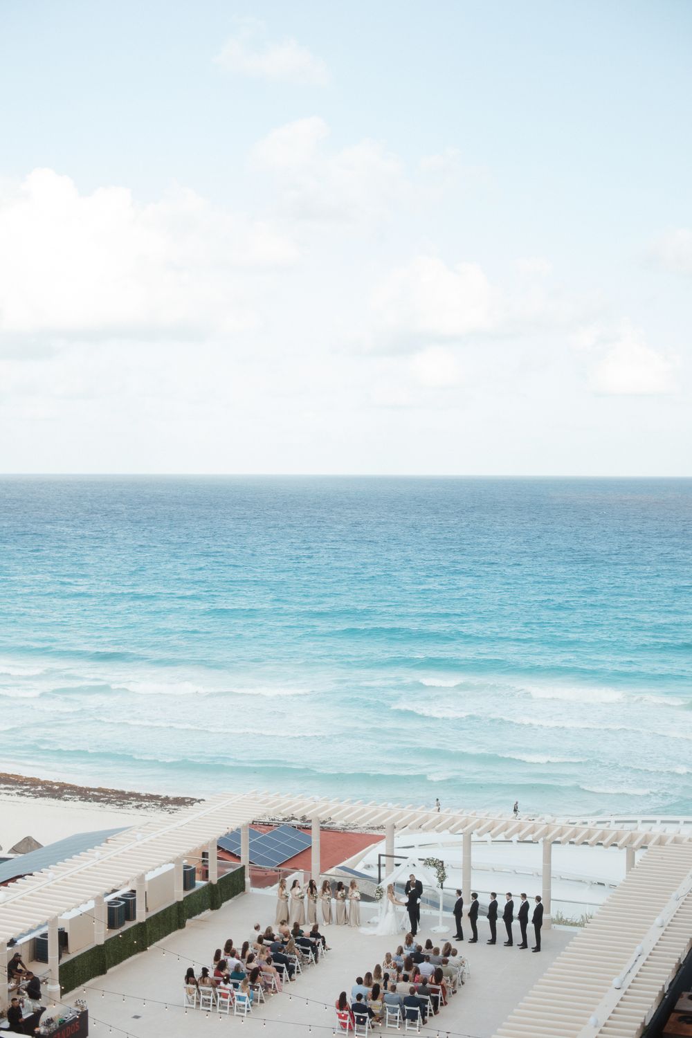 Elegant outdoor beach wedding ceremony overlooking turquoise ocean waters at a luxury resort venue.
