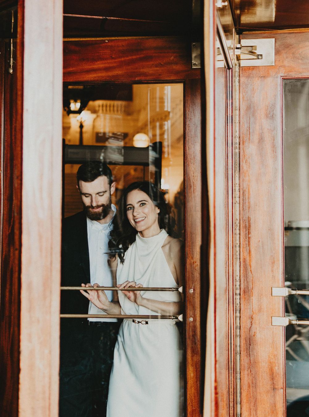 A couple stands intimately in a wooden doorway of a rustic restaurant.