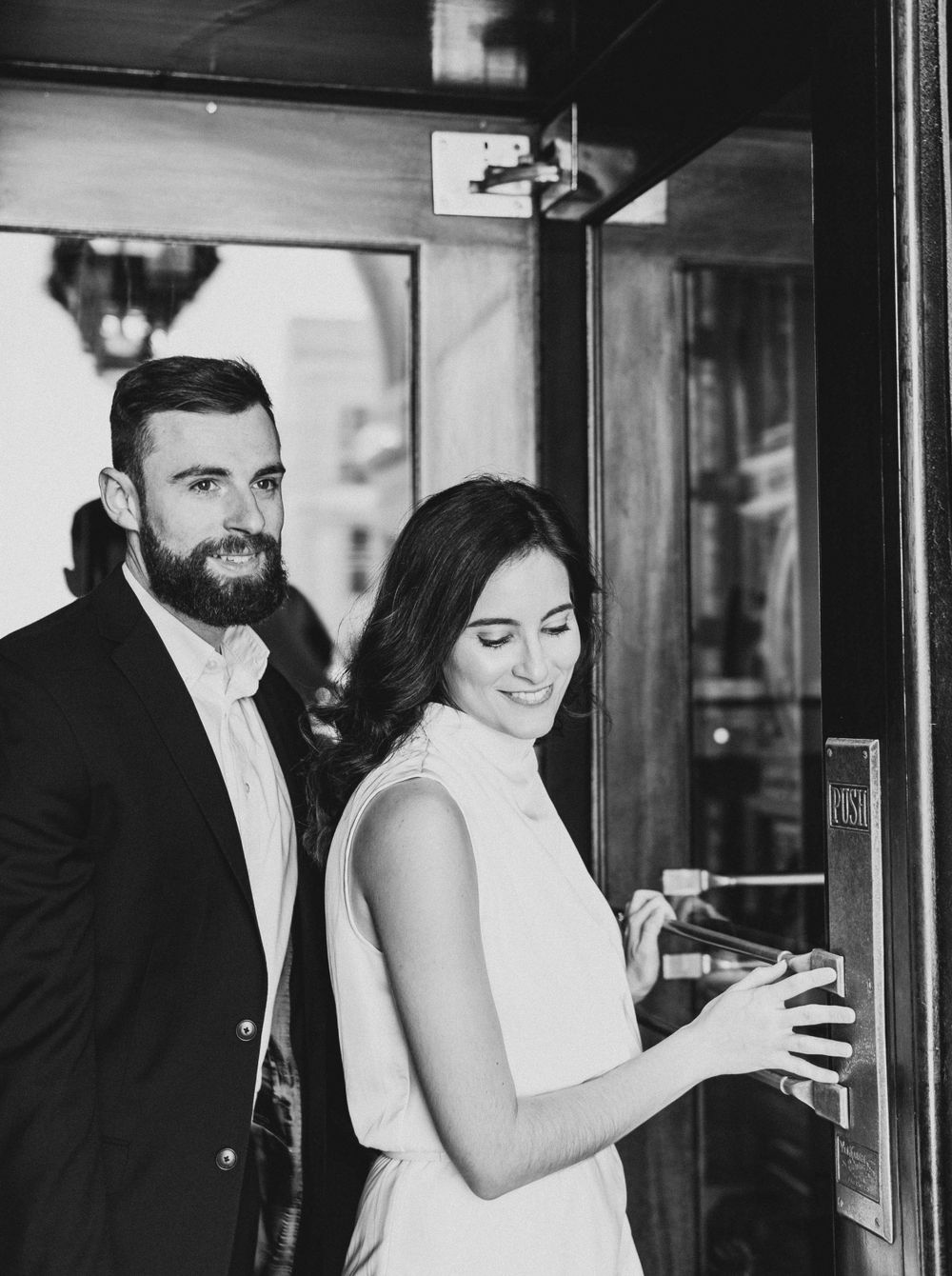 A couple shares a moment together while entering an elegant establishment.