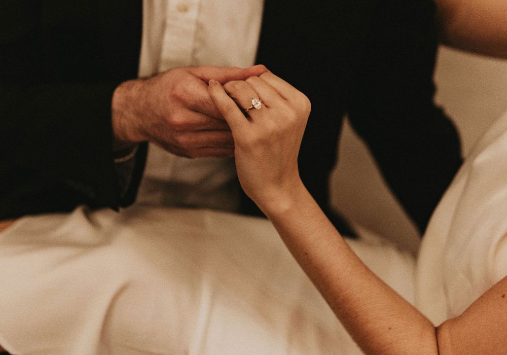 Close-up of hands clasped together showing wedding rings and intimate connection.