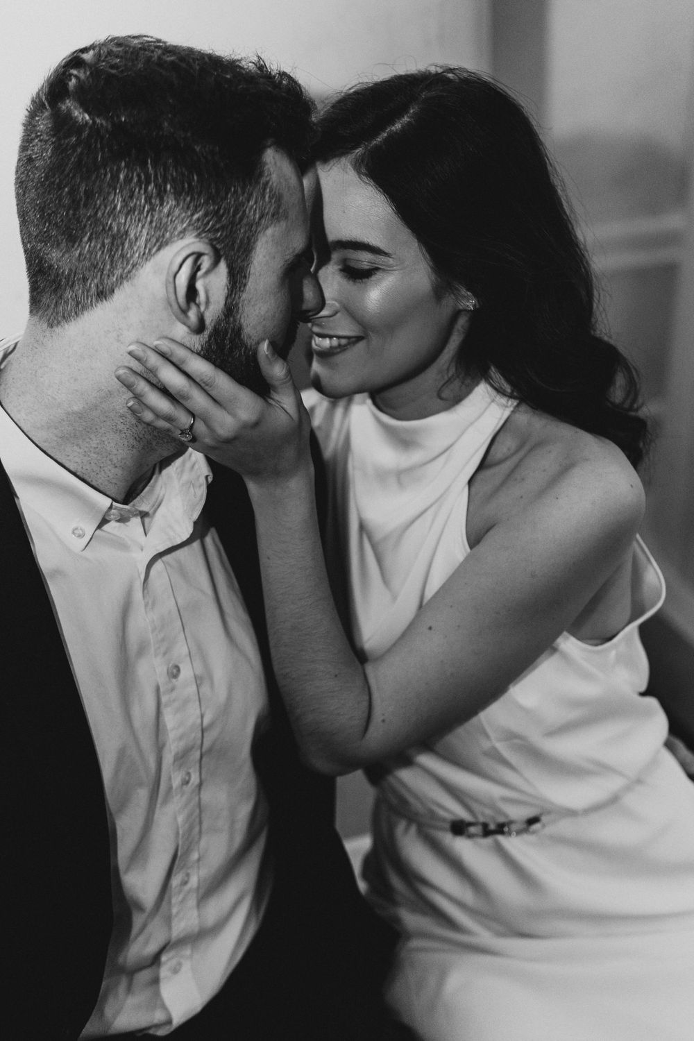 An intimate black and white portrait of a couple sharing a tender moment.