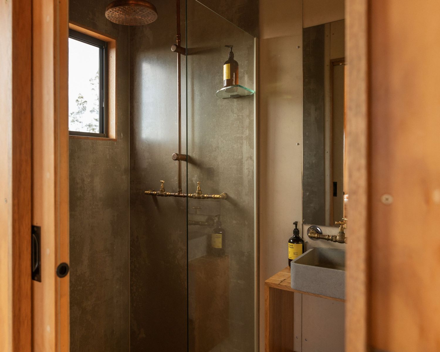 Modern minimalist bathroom interior with glass shower enclosure and wooden accents. Unyoked Cabin in Queensland.