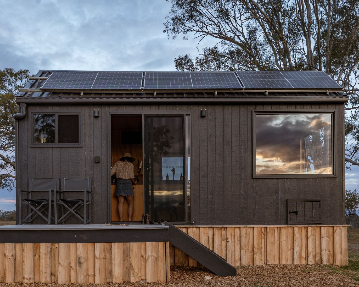 Eco-friendly Unyoked Cabin in Queensland. Outdoor photo of tiny house with solar panels and wooden exterior at dusk.