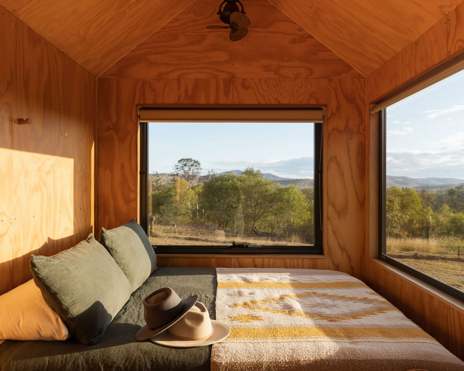 Cozy window nook with cushions overlooking mountain landscape through large picture window. Unyoked Cabin in Queensland.