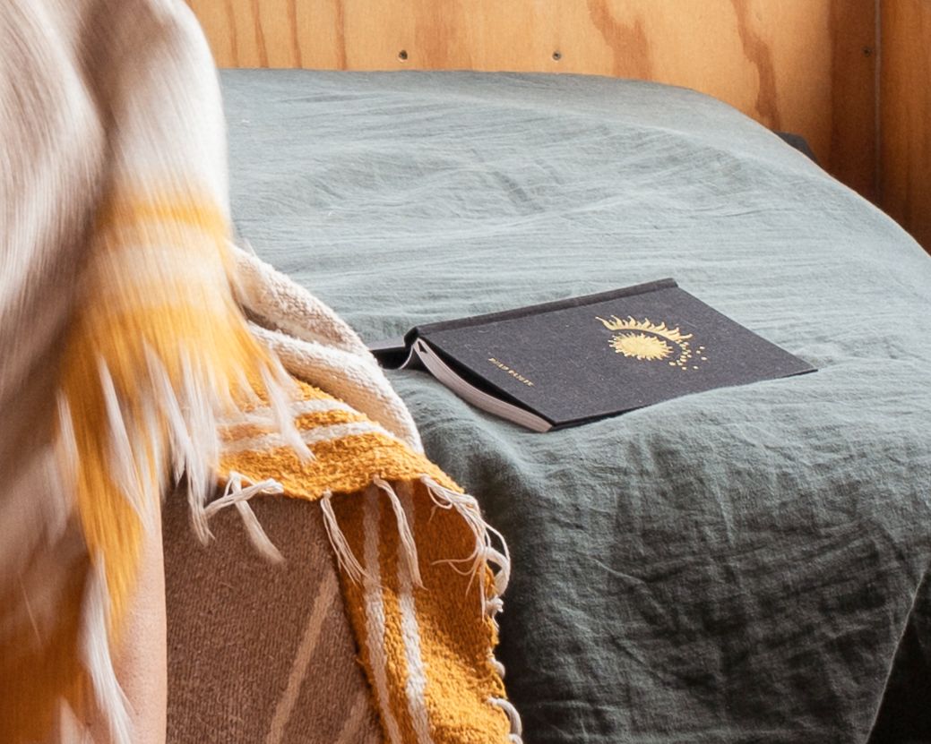 Minimalist bedding with yellow accents and passport on grey linen sheets.