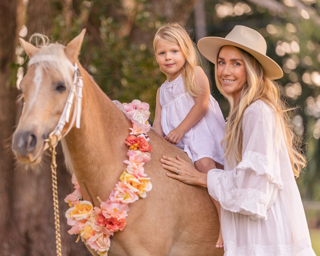 Romantic photoshoot featuring a horse adorned with peach-colored flowers in a natural setting.