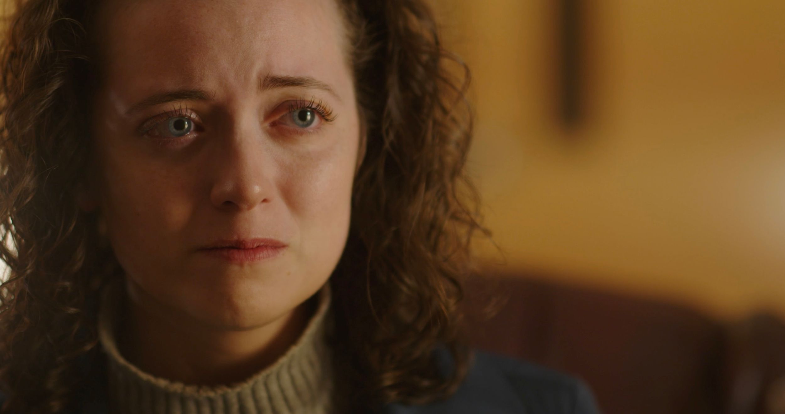 Close up dramatic portrait shot with warm lighting and cream colored sweater.