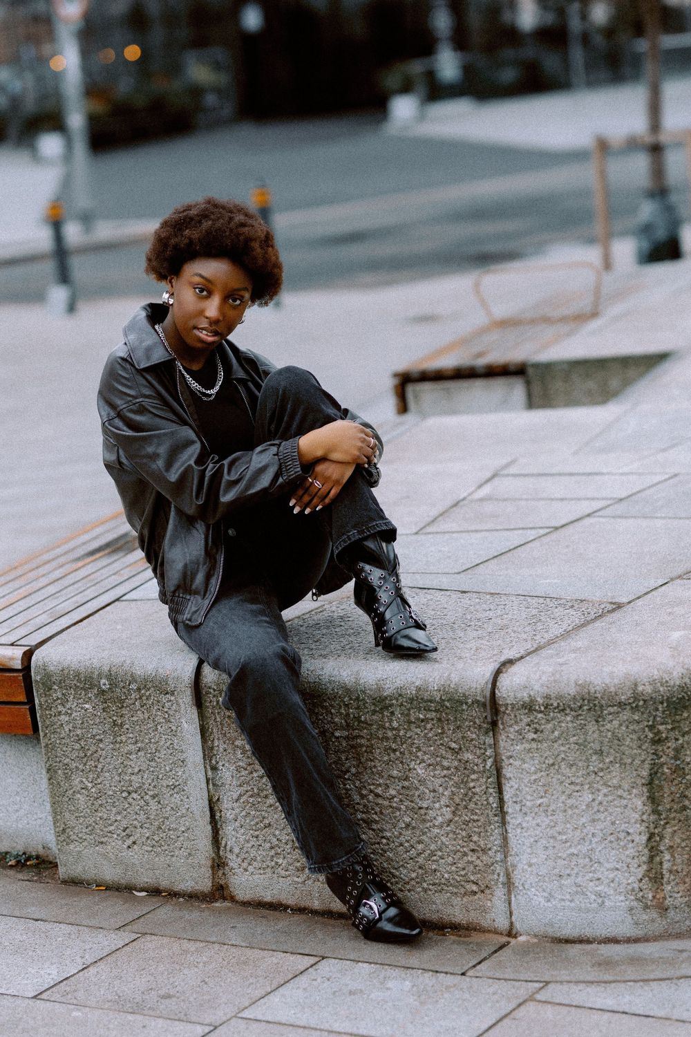 A sequence of photos showing someone sitting and posing on concrete steps in an urban setting.