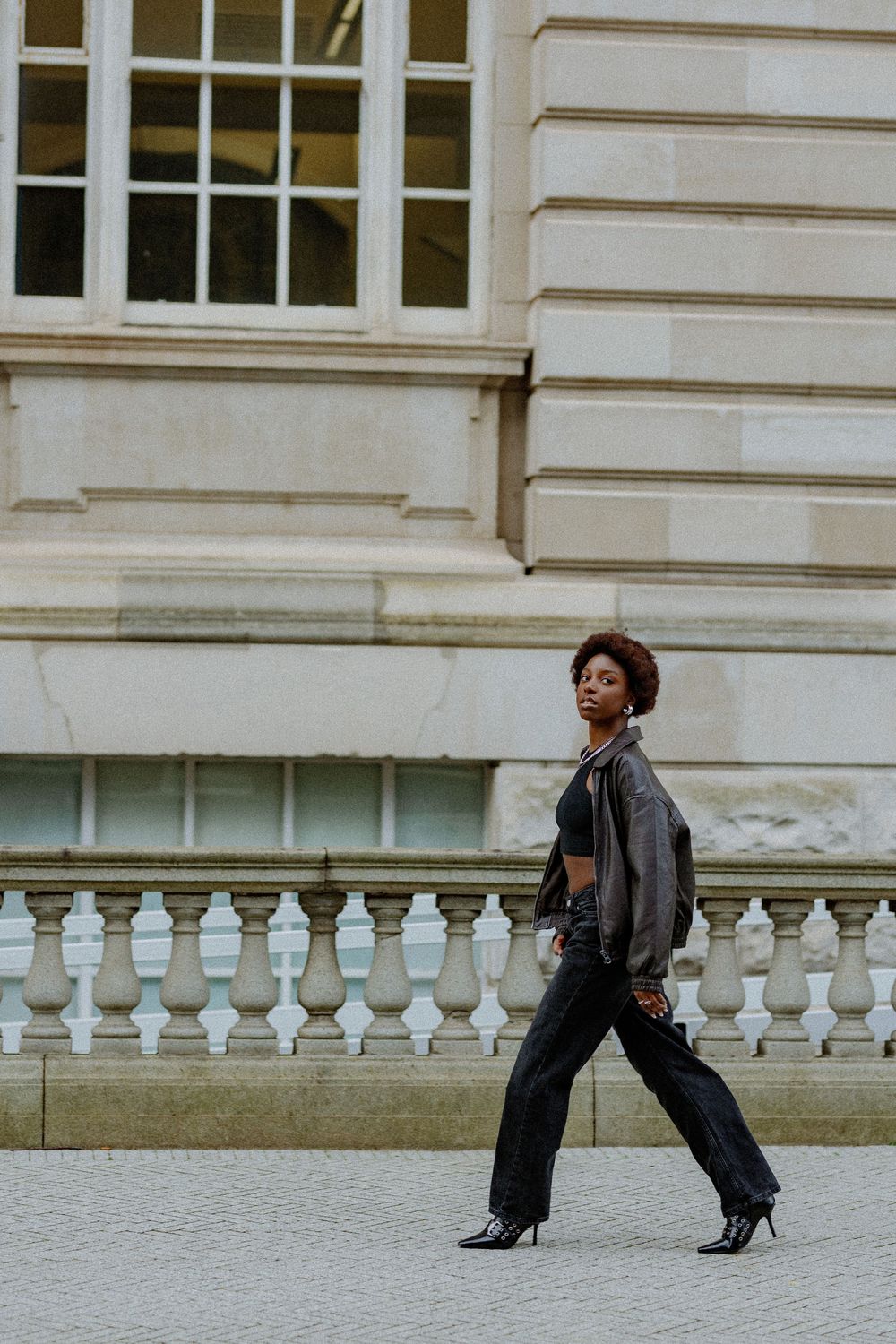 Dynamic dance poses captured against architectural backdrop with white stone balustrade and building exterior.